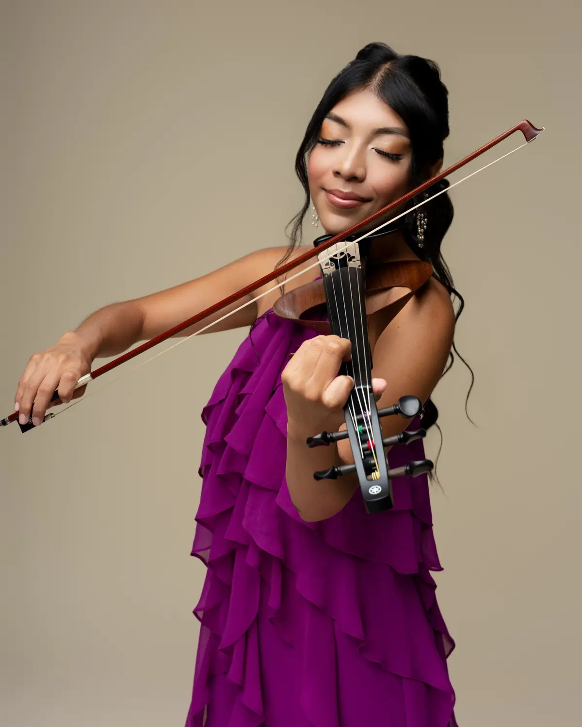 Bets performing on her electric violin in a purple gown