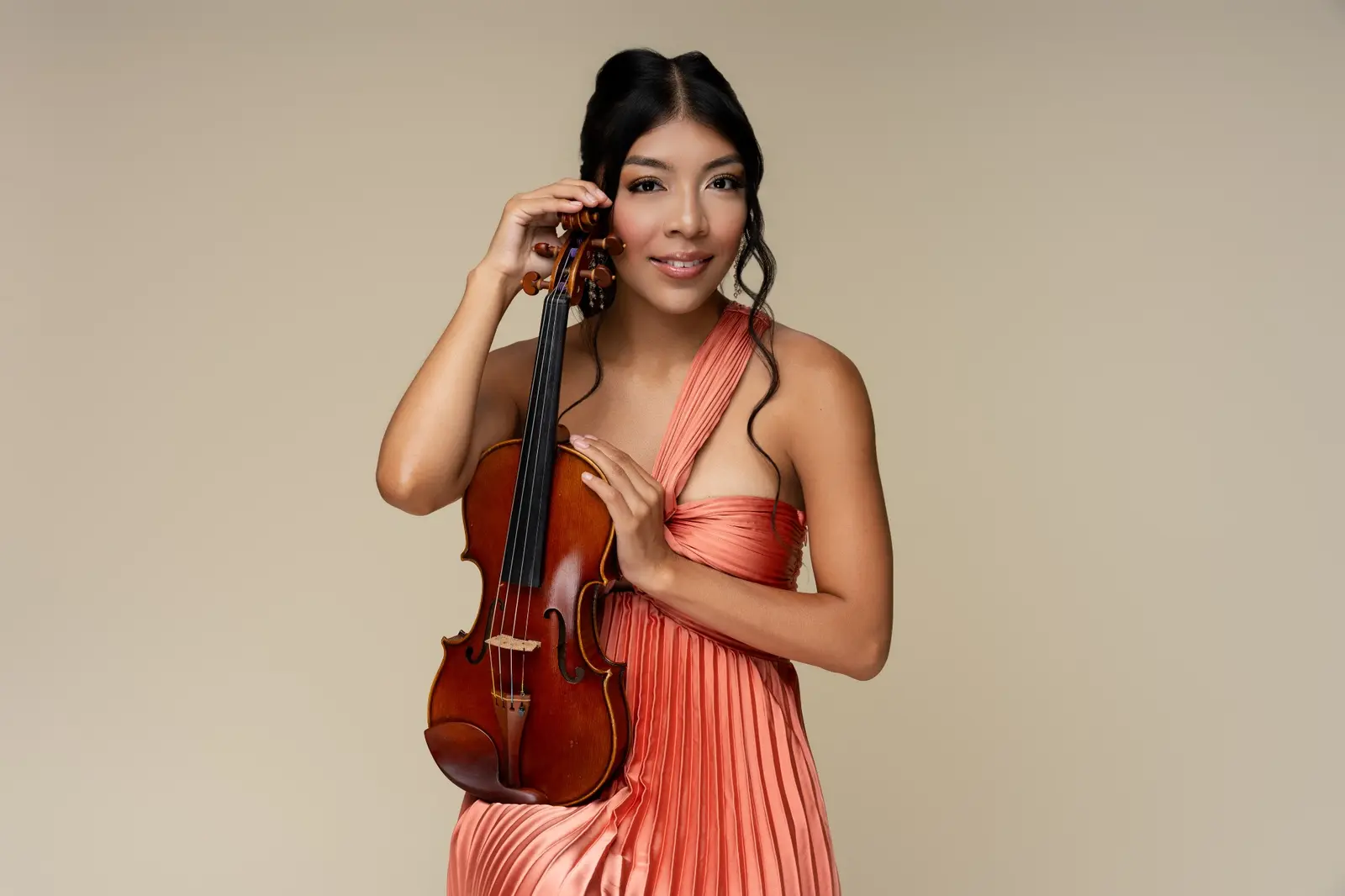 Portrait of Bets in a coral gown holding her acoustic violin